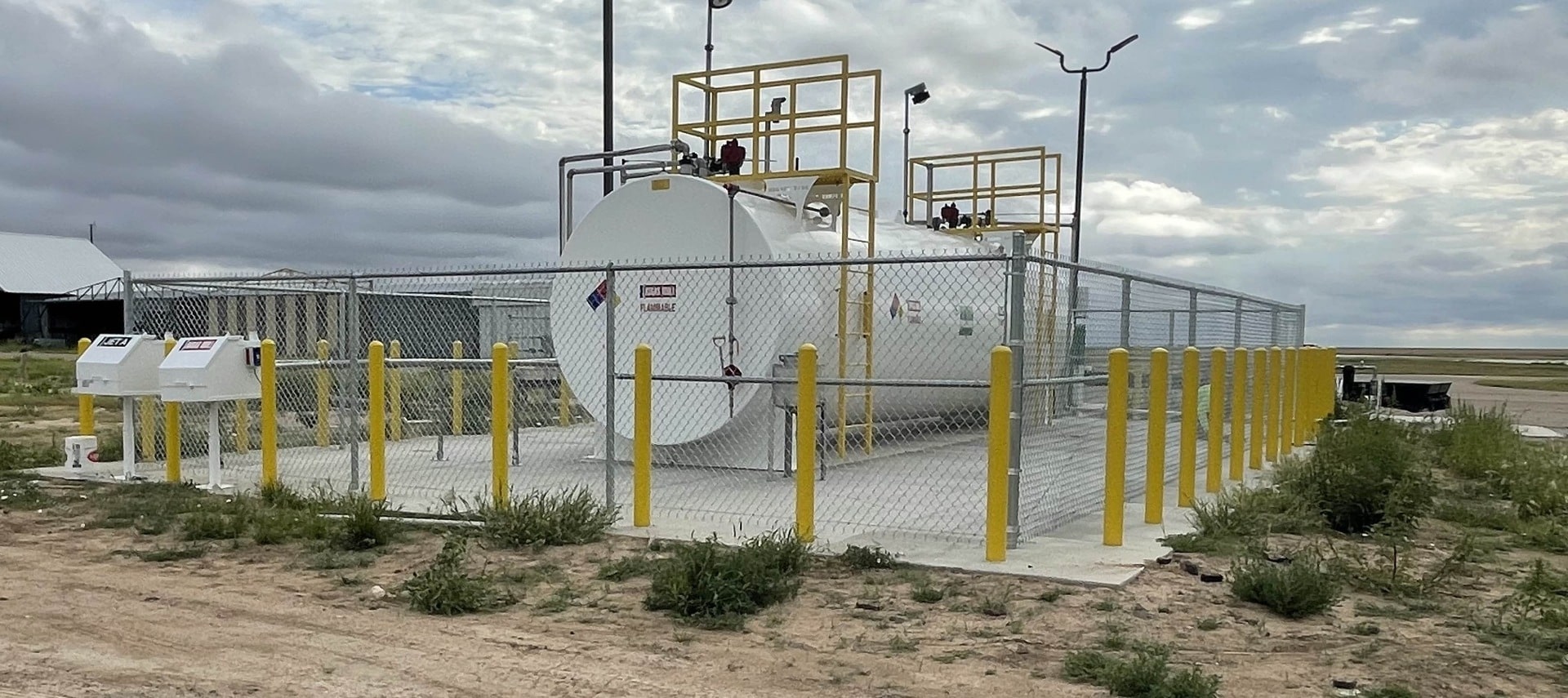 Secure fuel storage facility protected by chain-link fencing and safety bollards.
