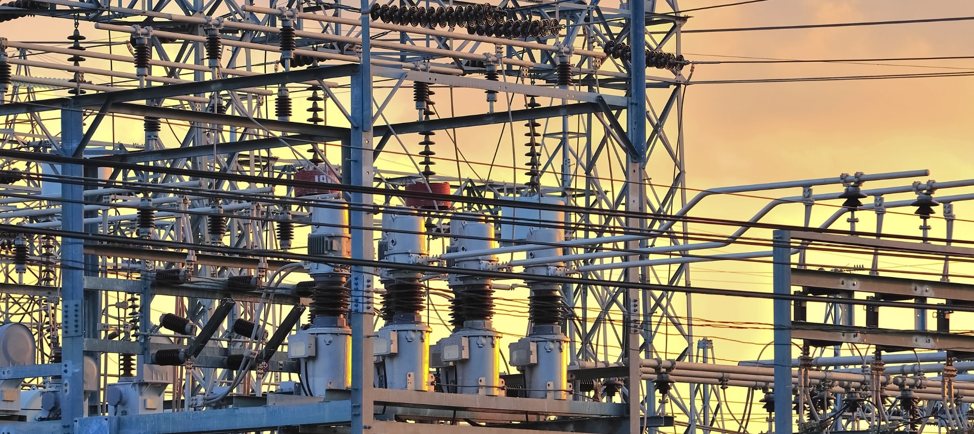 Electric power plant infrastructure with secure perimeter fencing at sunset.